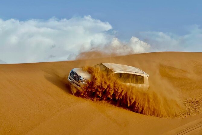 Dubai Desert Safari: Dune Bashing, Camel Ride, Sandsurf & 5<em> BBQ – Five Things to Know Before You Go’ /></p>
<ul>
<li><strong>Lahbab’s red dunes are the main event:</strong> The sand here provides a more striking setting for dune bashing and sunset photographs.</li>
<li><strong>Your 4×4 ride lasts about two hours:</strong> That includes stops for sandboarding, photos, water, restrooms, and a short break before the camp.</li>
<li><strong>The camp offers more than dinner:</strong> Expect henna, Arabic clothing, falcon photographs, shisha opportunities, camel feeding, and live performances.</li>
<li><strong>The $27.91 price covers a lot:</strong> Transport, the safari, soft drinks, sandboarding, a camel experience, and a buffet are included.</li>
<li><strong>Quad bikes and VIP seating cost extra:</strong> Quad bikes are listed at $50, while shisha, alcohol, and a VIP table are not included.</li>
<li><strong>The shared format keeps costs down:</strong> You ride in a shared 4×4 and visit a shared camp, with a maximum group size of 100 people.</li>
</ul>
<h2 id="why-lahbab-makes-this-safari-worthwhile">Why Lahbab Makes This Safari Worthwhile</h2>
<p><img width="669" height="446" decoding="async" src=